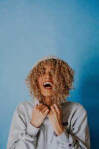 woman with curly hair wearing a hoodie. 