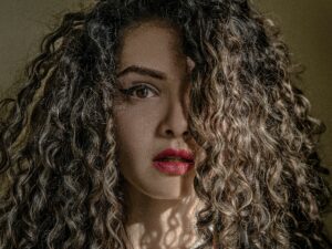 woman with curly hair covering half her face. 